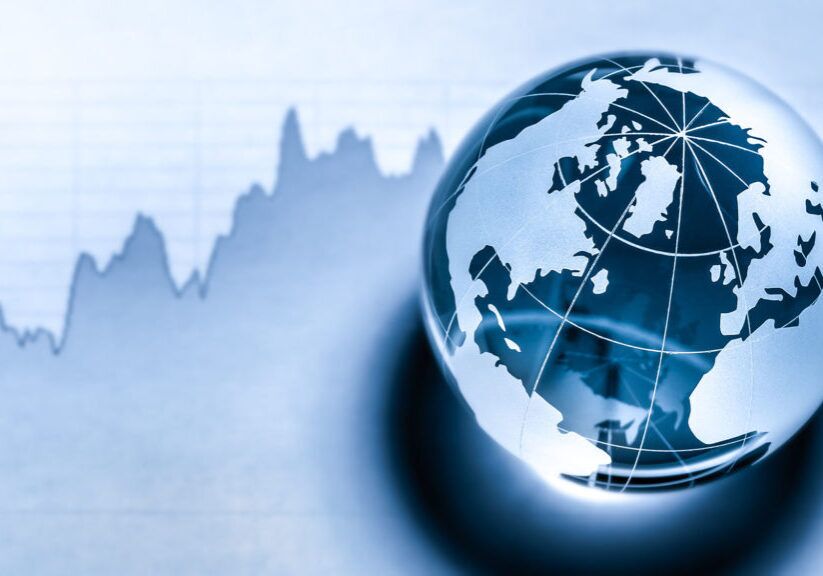 Image of an etched glass globe paperweight in front of what looks like a financial chart