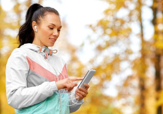 active woman in autumn park and looking at her phone