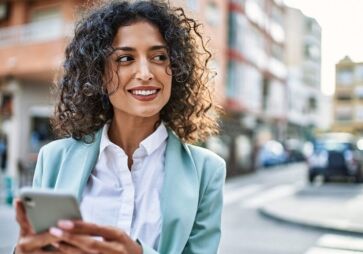 Young business woman wearing professional outfit in the city using smartphone