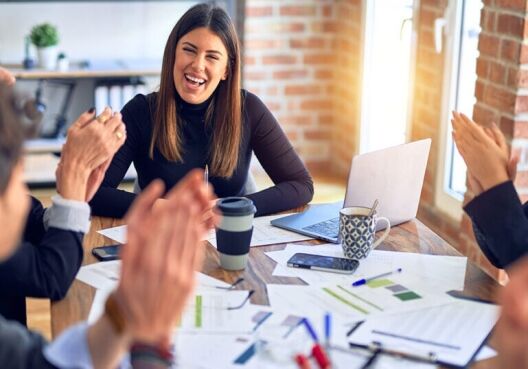 employees celebrating a team member on their accomplishment in a meeting